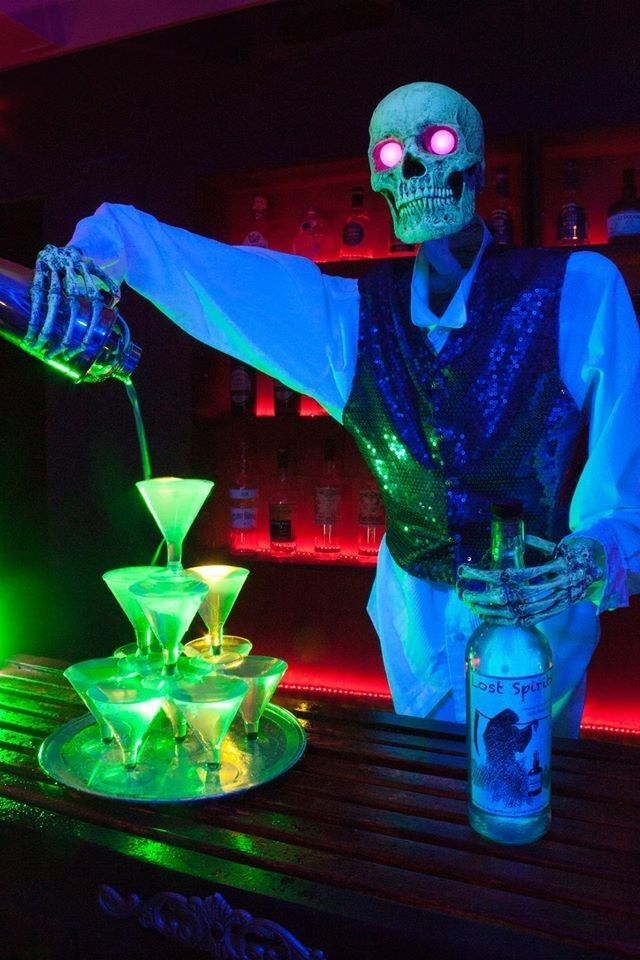 a skeleton bartender is pouring some drinks into the glasses in front of neon colored lights