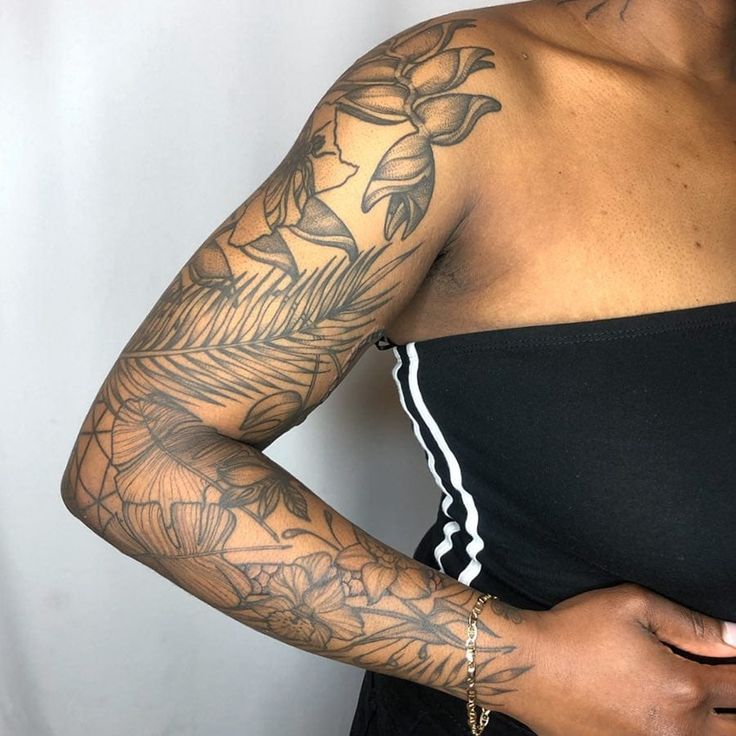 a woman with tattoos on her arm and shoulder holding a cell phone in her hand