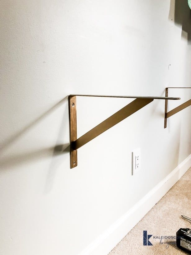 there is a wall mounted shelf on the wall with a metal bar attached to it