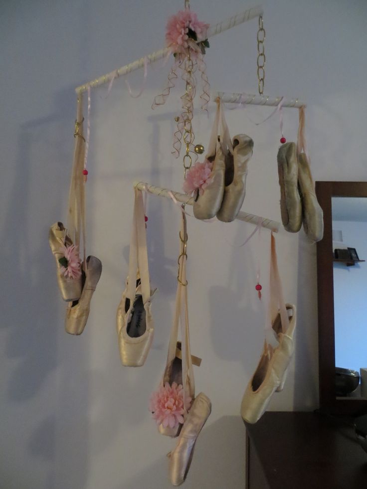 several pairs of ballet shoes hanging on a wall with flowers and ribbons attached to them