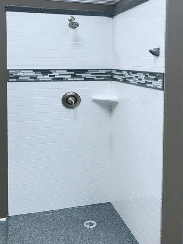 a white shower with black and gray tile on the floor, walls and ceiling in a bathroom