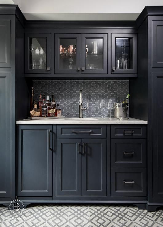 a kitchen with black cabinets and marble counter tops