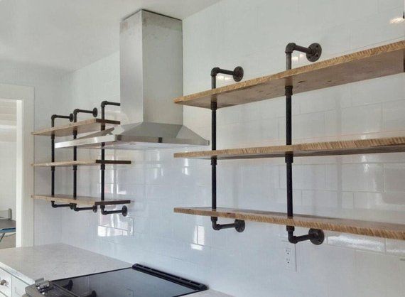 a stove top oven sitting inside of a kitchen next to open shelving units on the wall