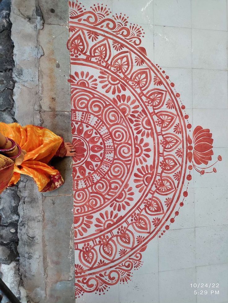 an orange umbrella sitting on the side of a building next to a wall with designs painted on it