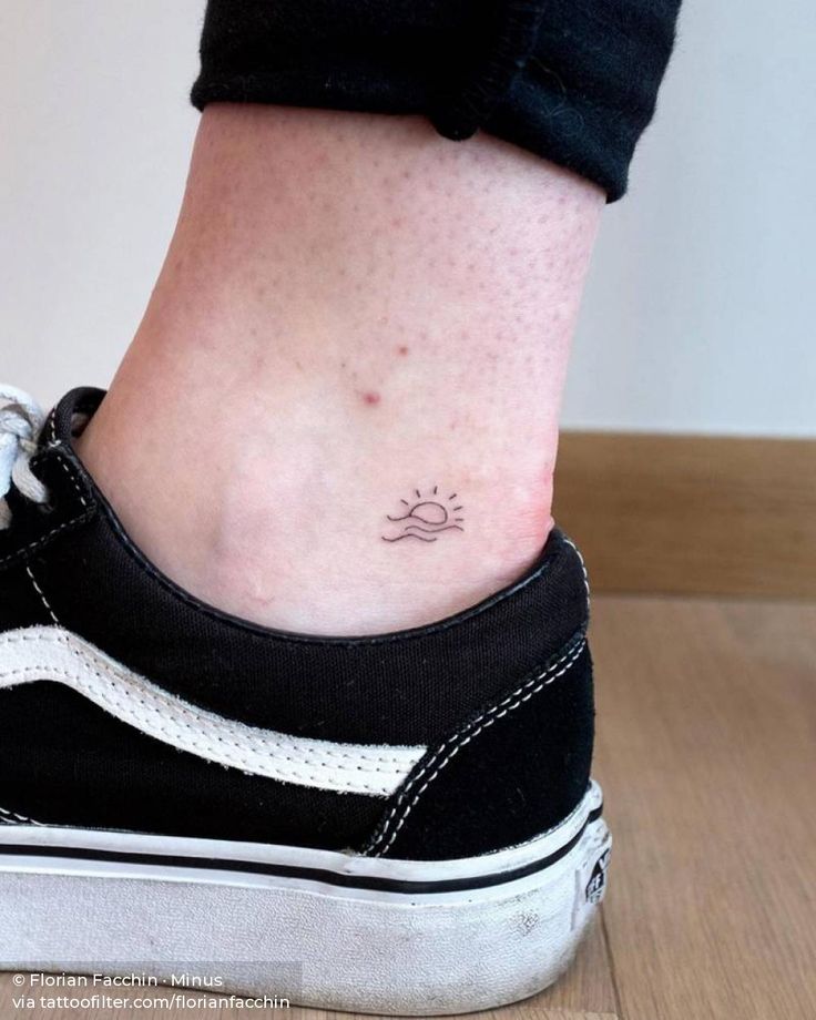 a woman's foot with a small sun tattoo on her left side ribcage