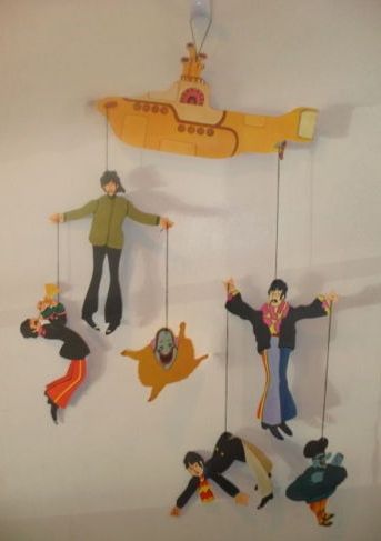 a group of people hanging from strings in front of a yellow submarine shaped wall decoration