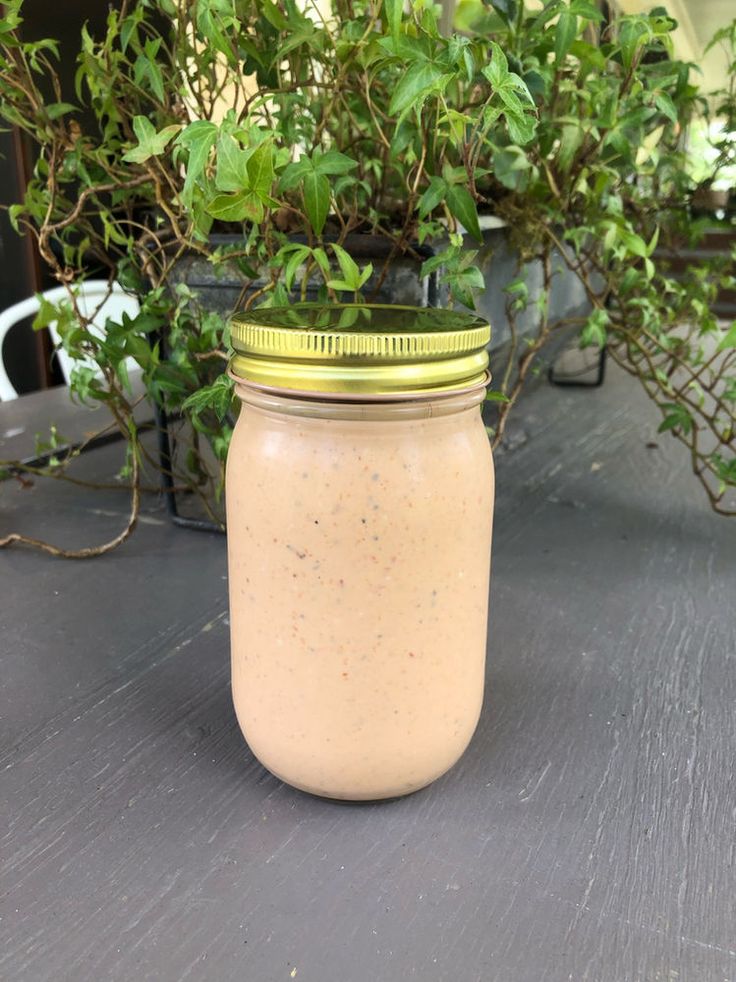 a jar filled with liquid sitting on top of a table next to a potted plant