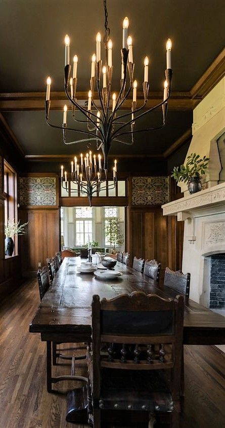 a large dining room table and chairs in front of a fireplace with candles on it