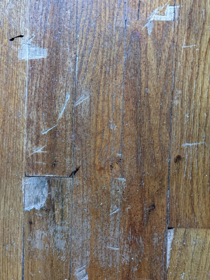 the wood floor is peeling and chipping with white paint on it's surface