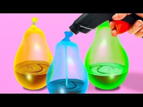 three different colored water bottles being held by a person's hand with an object in the background