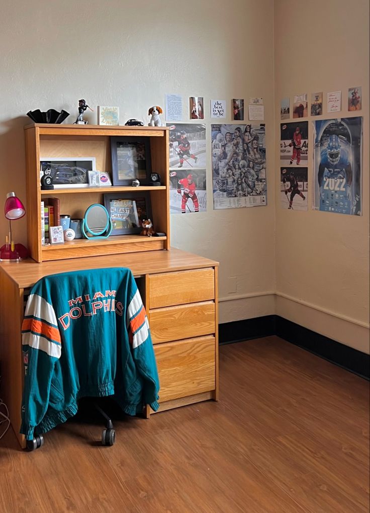 a room with a wooden desk and some pictures on the wall next to an open bookcase