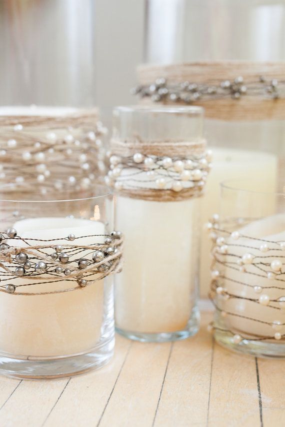 candles are lined up on the table with pearls and beads around them in glass jars