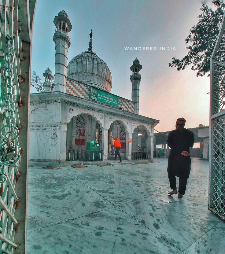 a man standing in front of a white building with two minarets on it