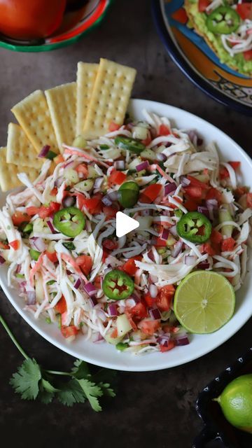 a white plate topped with coleslaw and crackers next to lime wedges