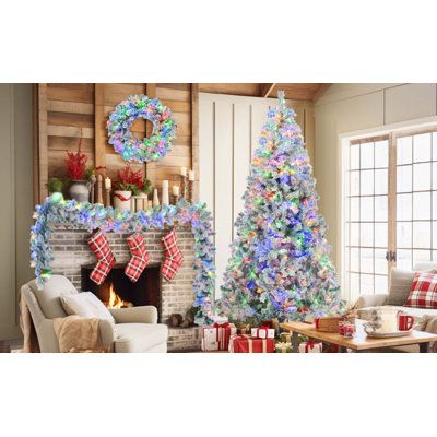 two decorated christmas trees sitting in front of a fireplace with presents on the mantles