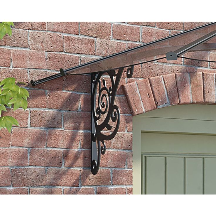 the corner of a brick building with an iron bracket on it's side and a green door