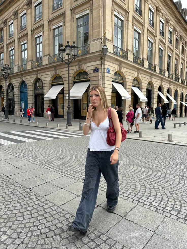 Girls outfit inspo aesthetic paris parisian architecture french buildings black and white crossing putfit insporation french girl red bag black cargos white top jewellery cigarette summer in paris european summer travel travelling girls outfit #paris #outfit #outfitinspo #itgirl #europe #aesthetic Black Bag Outfit Summer, Red Handbag Outfit Street Style, Vintage Red Bag Outfit, Spring Outfits Germany, Red Bags Aesthetic, Red Purse Outfit Summer, Red Bags Outfit, Red Bag Outfit Summer, Purse Aesthetic Outfit