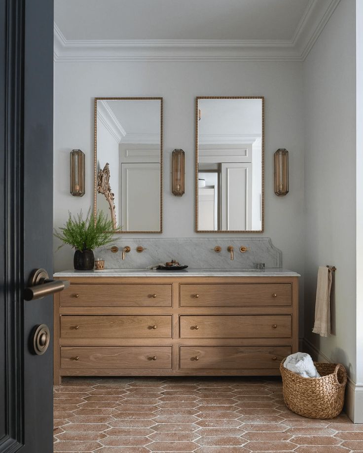 a bathroom with two mirrors above the sinks and a basket on the floor next to it