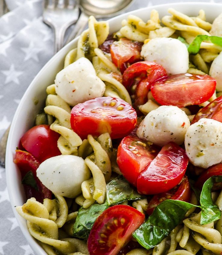 a pasta salad with tomatoes, mozzarella and spinach