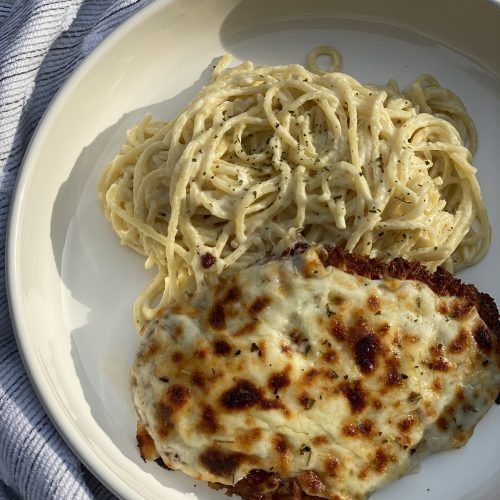 a white plate topped with pasta and meat covered in sauce on top of a blue towel