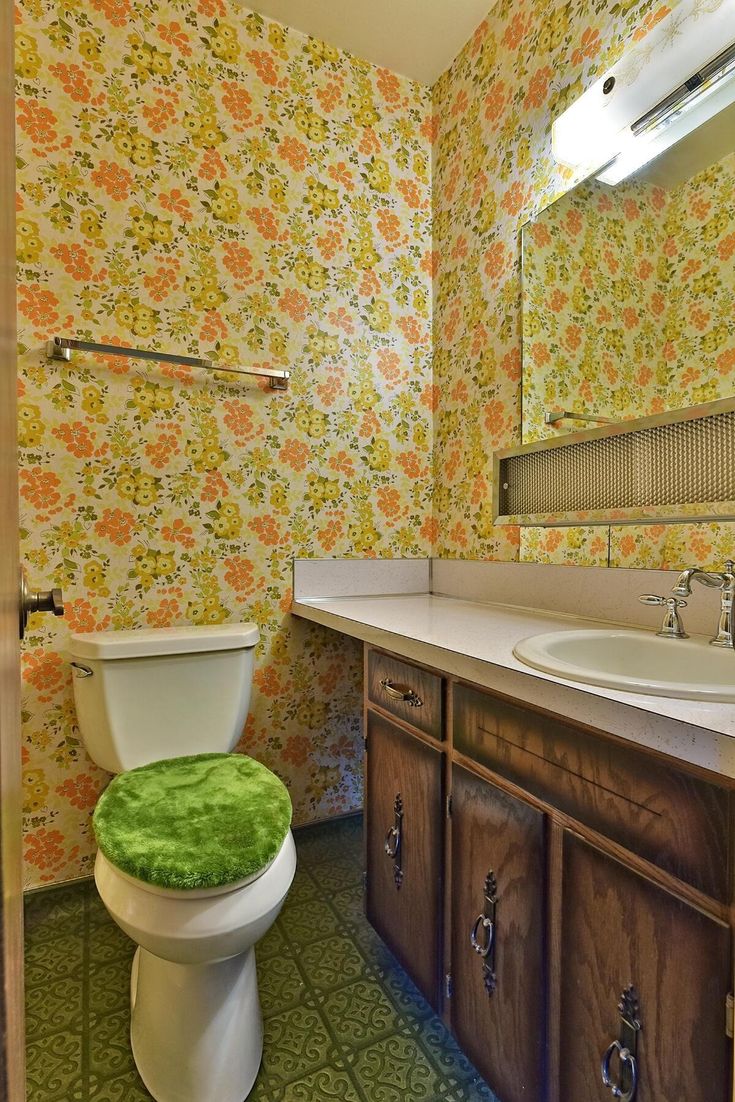 a bathroom with floral wallpaper and green rug on the floor next to a toilet