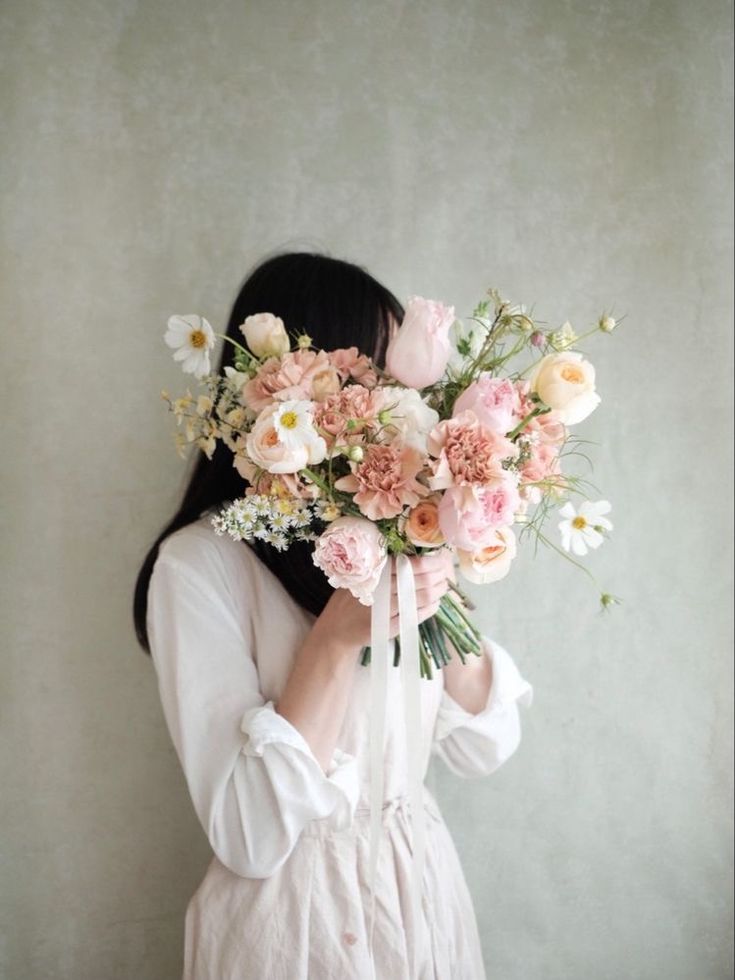 a woman holding a bouquet of flowers in front of her face