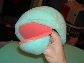 a hand holding a blue hat with a red band on it's side and the top part of its head