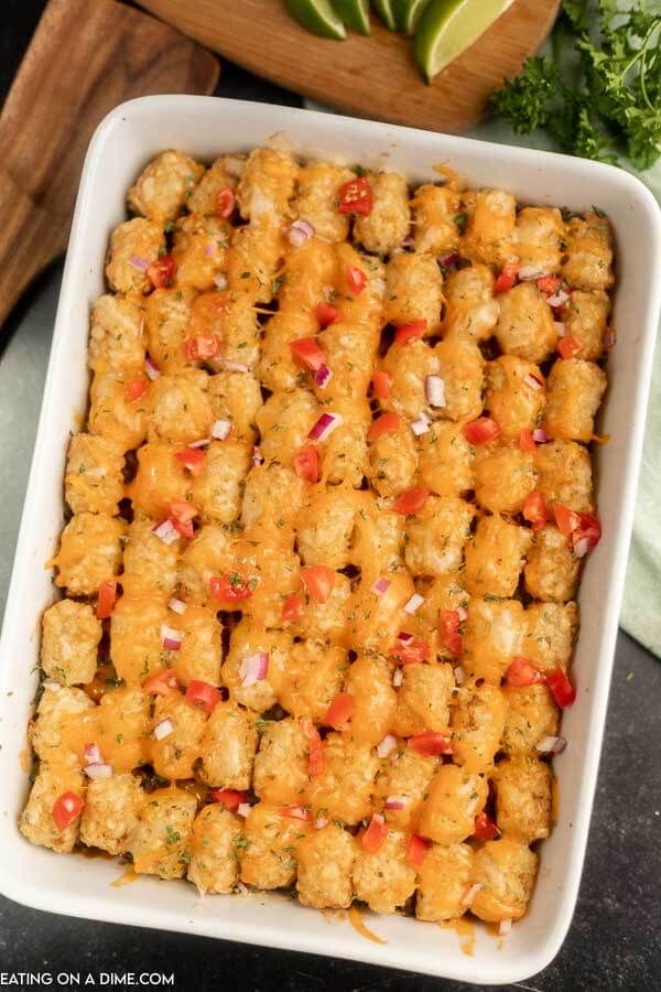 a casserole dish filled with tater tots and garnished with onions