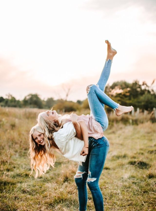 two women in jeans and pink shirts are doing an acrobatic dance on the grass