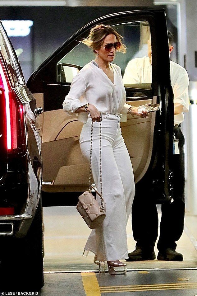 a woman in white is getting out of a car with her hand on the door handle