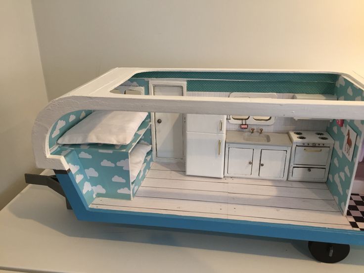 a doll house with blue and white furniture on wheels, including a kitchen area in the shape of a boat