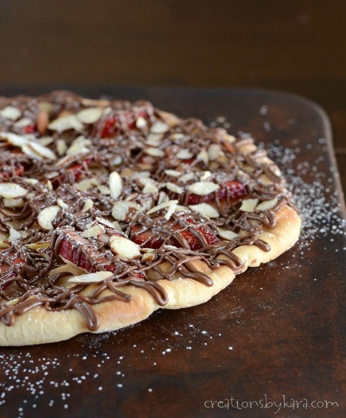 a pizza covered in chocolate and nuts sitting on top of a wooden cutting board with sprinkles