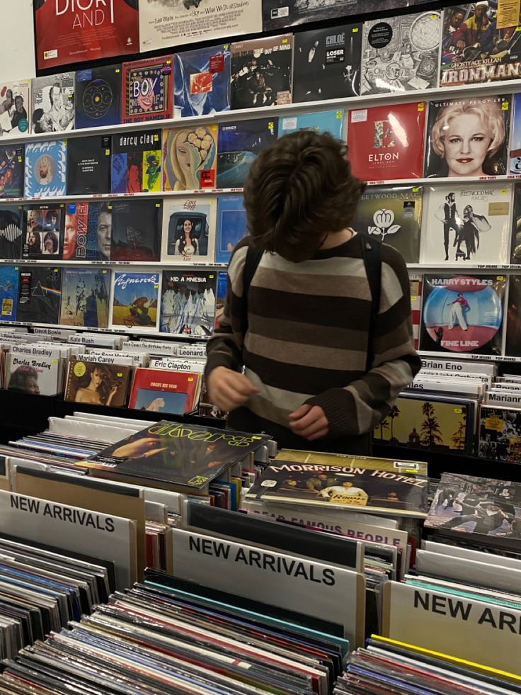 a person standing in front of a large amount of records on display at a store