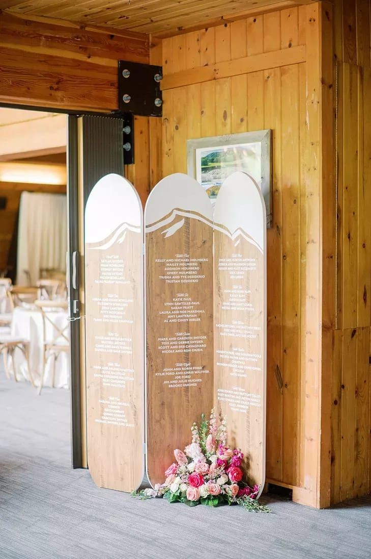 a wooden sign sitting on top of a floor next to a table covered in flowers