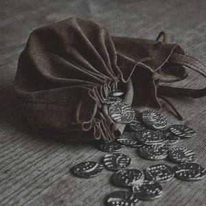 a drawstring bag filled with lots of coins on top of a wooden table