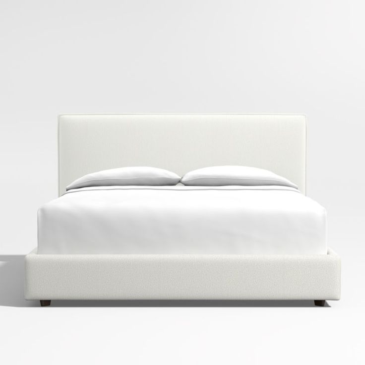 a bed with white sheets and pillows on it