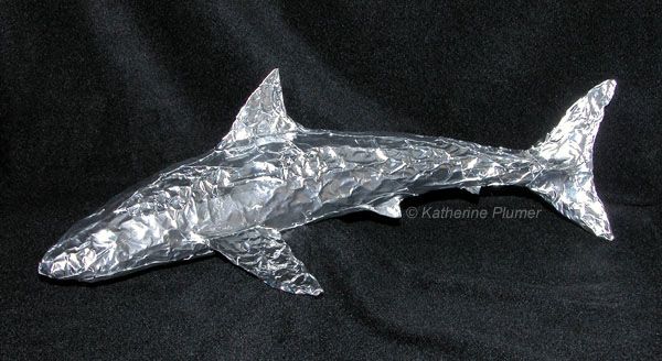 a shark made out of aluminum foil on a black background