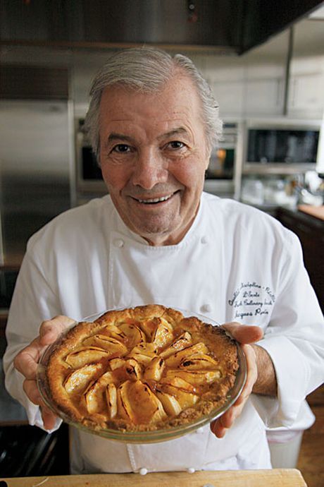 an older man holding a pie in his hands and smiling at the camera while wearing a chef's uniform