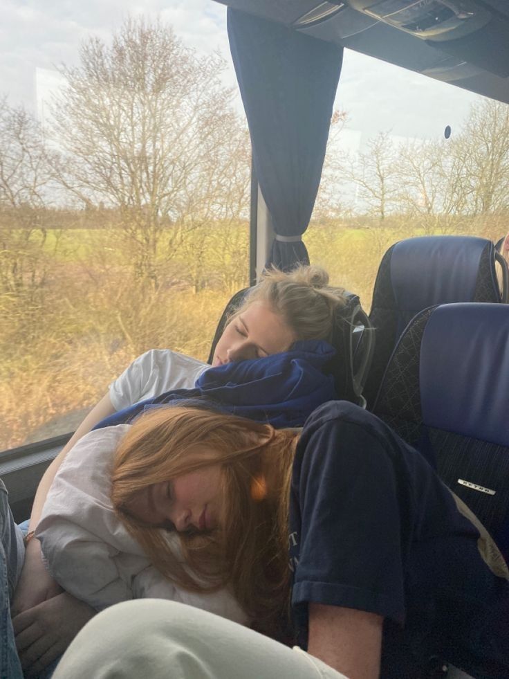 two people sleeping in the back of a bus with their heads on each other's shoulders