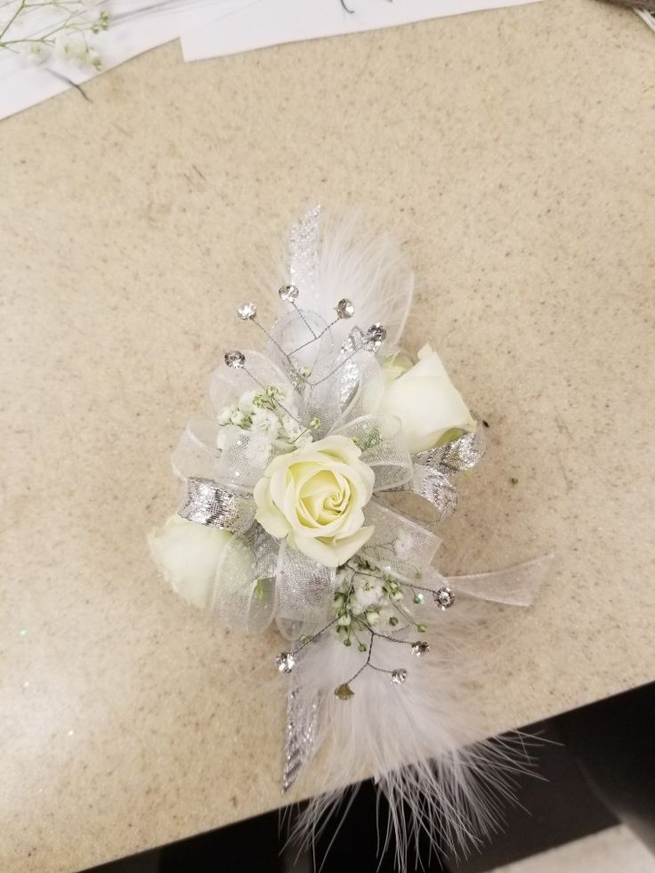 a white rose and feather corsage on a table