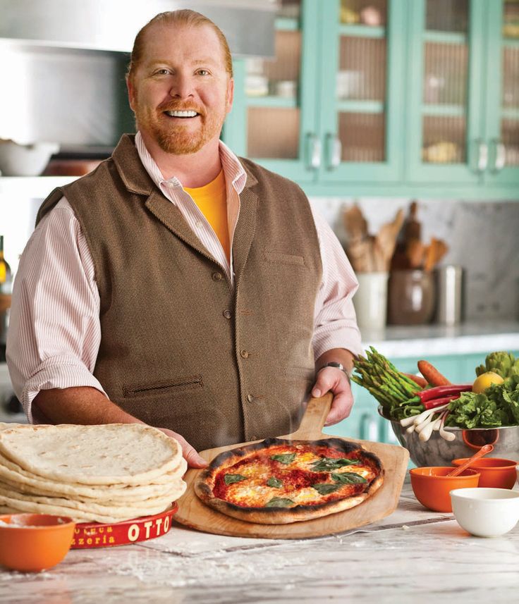 a man standing in front of a counter with pizzas and other foods on it