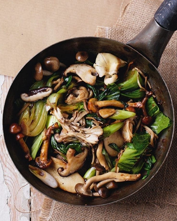 a pan filled with vegetables and mushrooms on top of a table