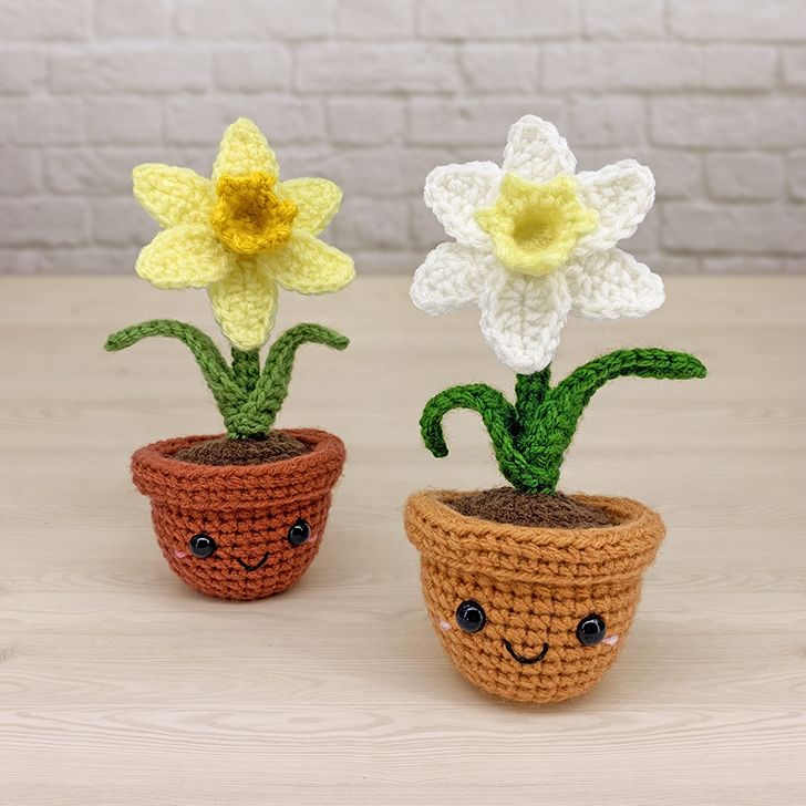 two crocheted potted plants with faces on them, one is yellow and the other is brown