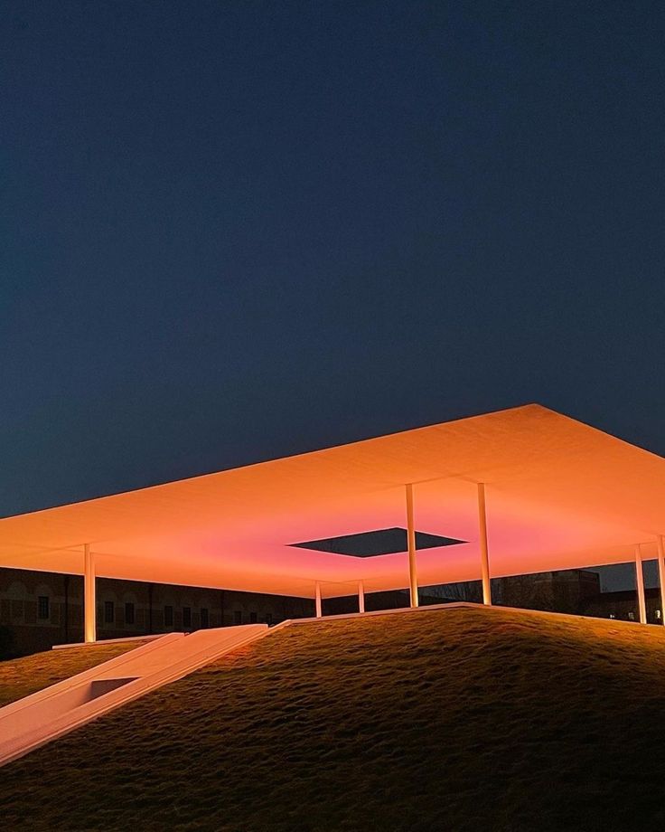 an illuminated structure on top of a hill at night