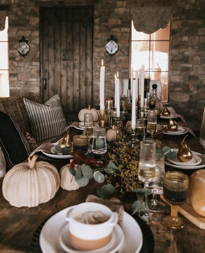 a dining room table is set with candles, plates and other decorations for thanksgiving dinner