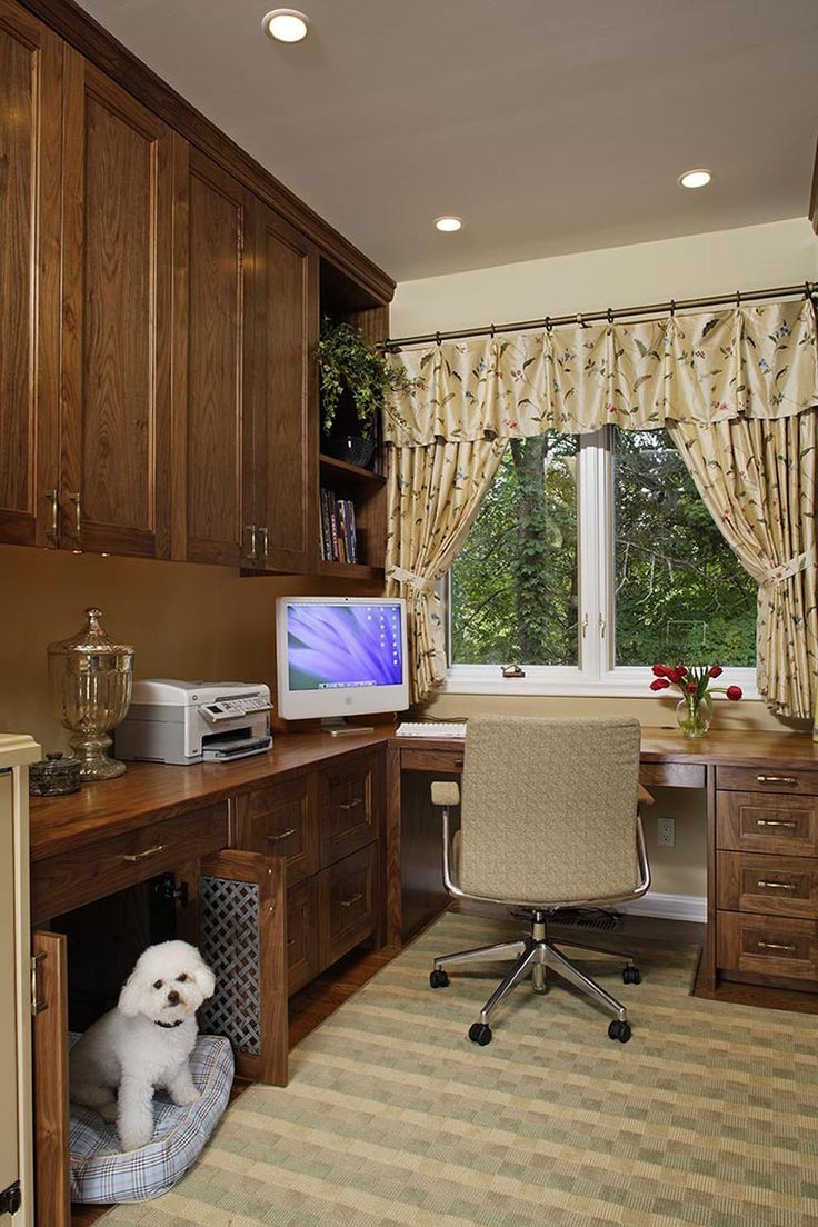 a dog sits in his kennel under the computer desk, which is built into the cabinets