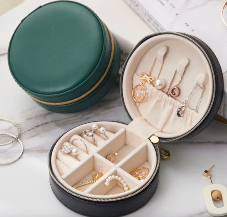 an open jewelry box sitting on top of a table next to rings and bracelets