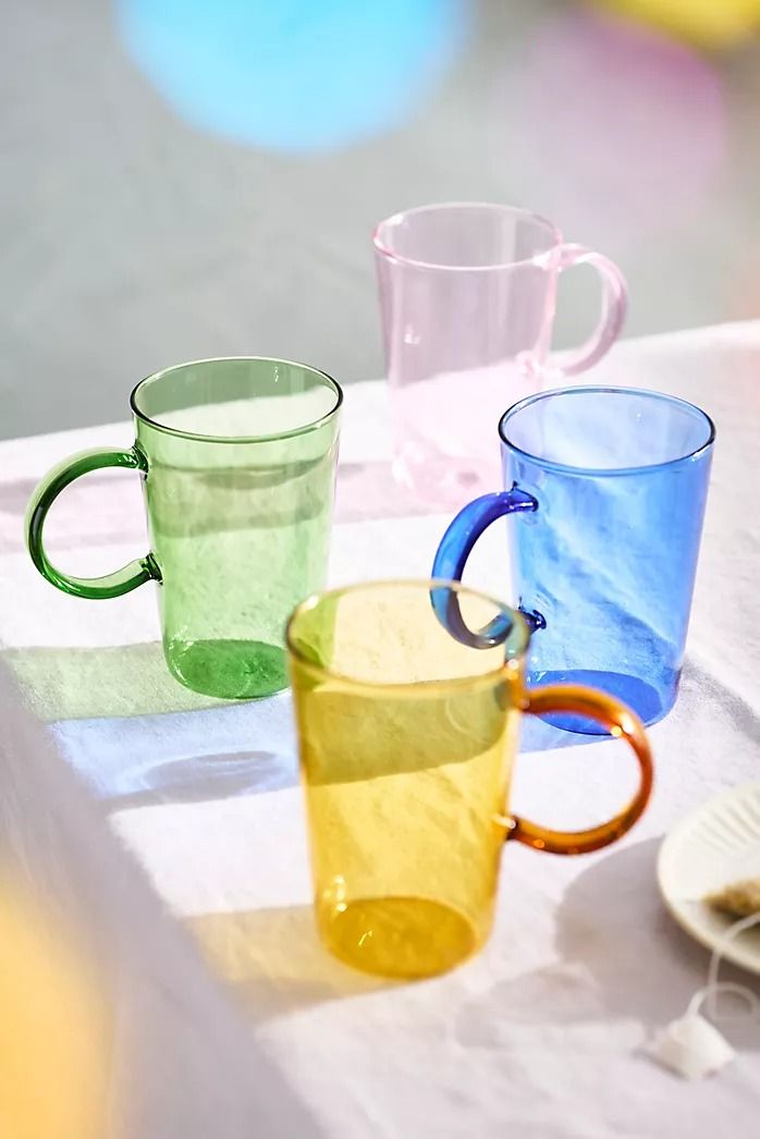 three different colored glass mugs sitting on a table