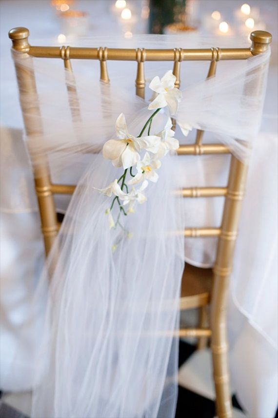 the chair is decorated with white flowers and tulle for an elegant touch to the table