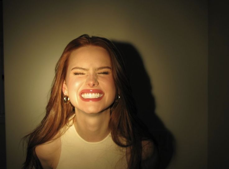 a woman smiling with her eyes closed in front of a light that is shining on her face